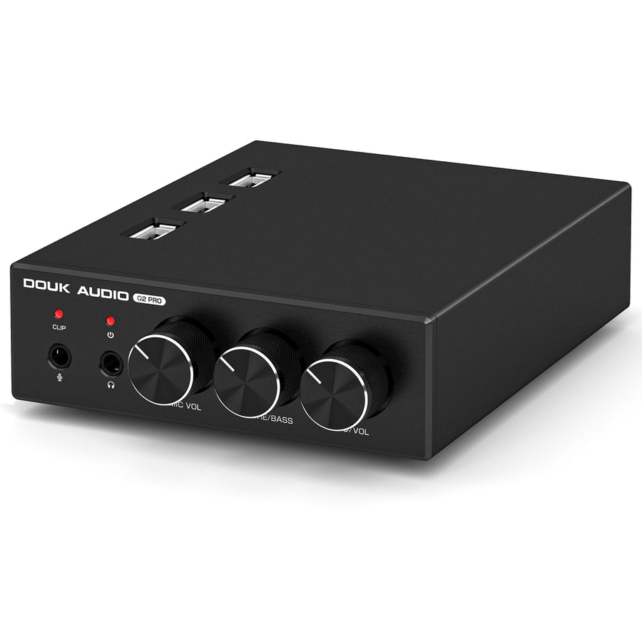 Compact black desktop audio interface labeled DOUK AUDIO Q2 PRO on a white background; three USB-A ports are recessed into the top, and the front holds two small red indicator LEDs, a microphone jack, a headphone jack, and three rotary knobs labeled MIC VOL, TRE/BASS and VOL