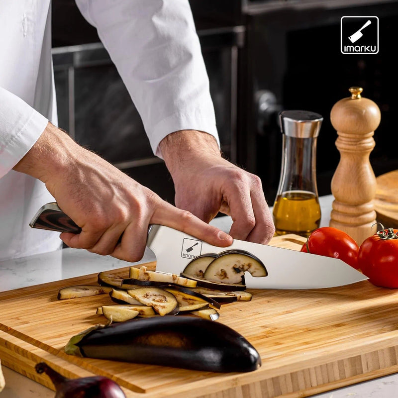 A chef knife with a wavy layered-steel blade and dark wooden handle photographed at a low angle against a dark background